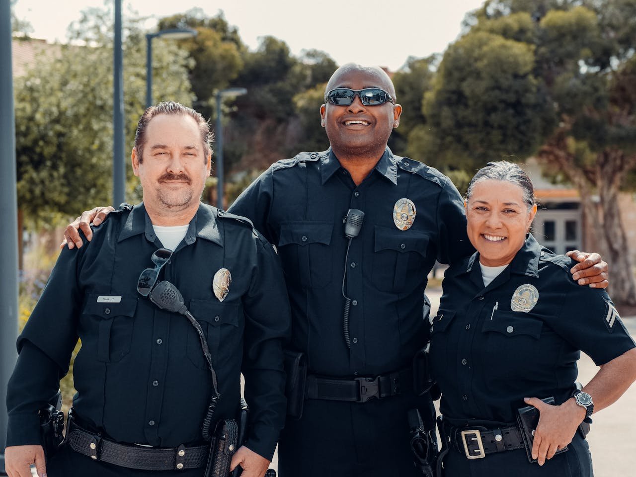 Services-03 Three police officers in uniform smiling together outdoors, symbolizing community and law enforcement.
